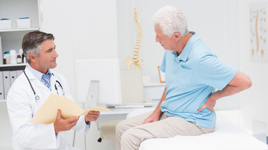 Patient zeigt dem Arzt, dass er Schmerzen im Rücken hat