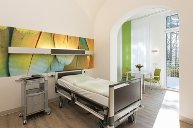 Patientenzimmer mit Pflegebett und Zugang zum Balkon auf der Palliativstation