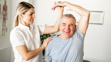 Physiotherapeutin beübt älteren Patienten 