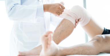 Ein Arzt verbindet einem Patienten das Knie