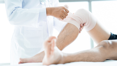 Ein Arzt verbindet einem Patienten das Knie
