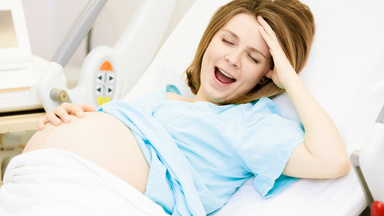 Eine schwangere Frau liegt in den Wehen