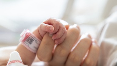 Eine Mutter hält die kleine Hand ihres Neugeborenen