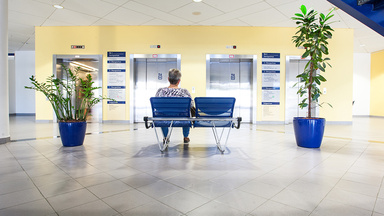 Eine Patientin sitzt vor den Fahrstühlen im Foyer am Standort Grimma