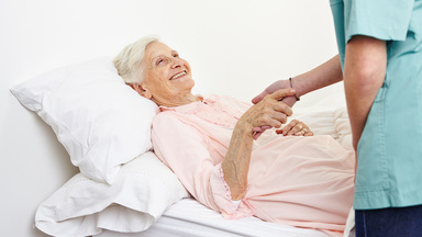 Pfleger hält die Hand einer älteren Patientin