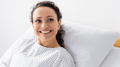 Eine Patientin liegt lächelnd im Bett