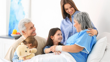 Eine ältere Patientin bekommt Besuch von ihren Enkelkindern